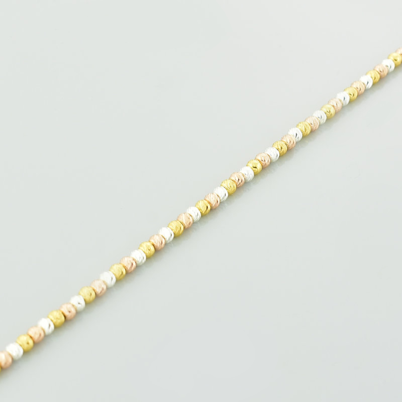 Bransoletka pozłacana z diamentowanymi kulkami w kolorze srebra oraz żółtego i różowego złota przedstawiona w zbliżeniu.