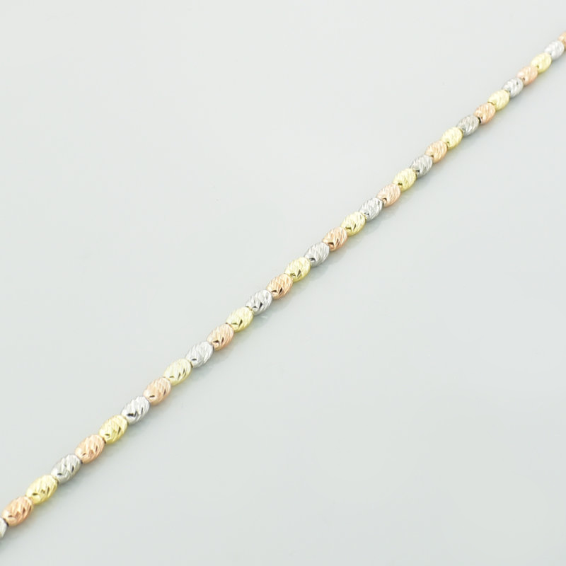 Bransoletka diamentowana z owalnych kulek w kolorze srebra oraz różowego i żółtego złota w zbliżeniu.