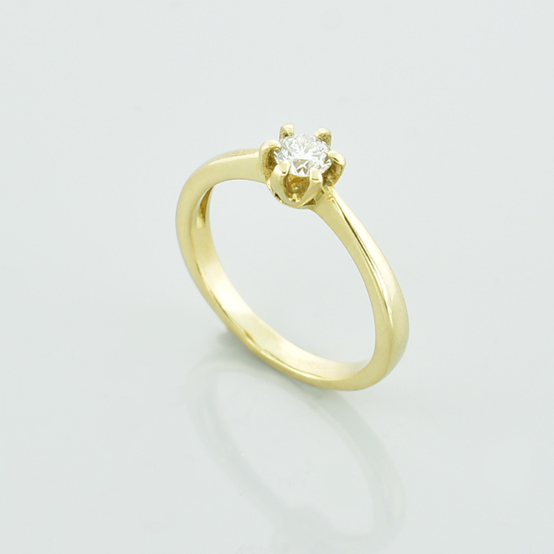 Klasyczny złoty pierścionek z białym brylantem.