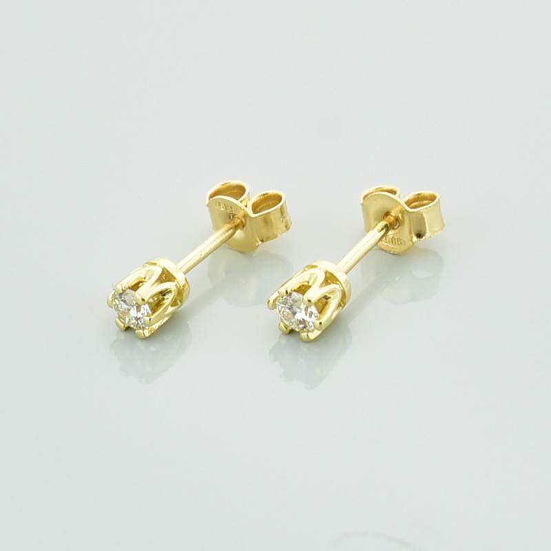 Złote kolczyki z białymi diamentami lub cyrkoniamii, zapinane na sztyft.