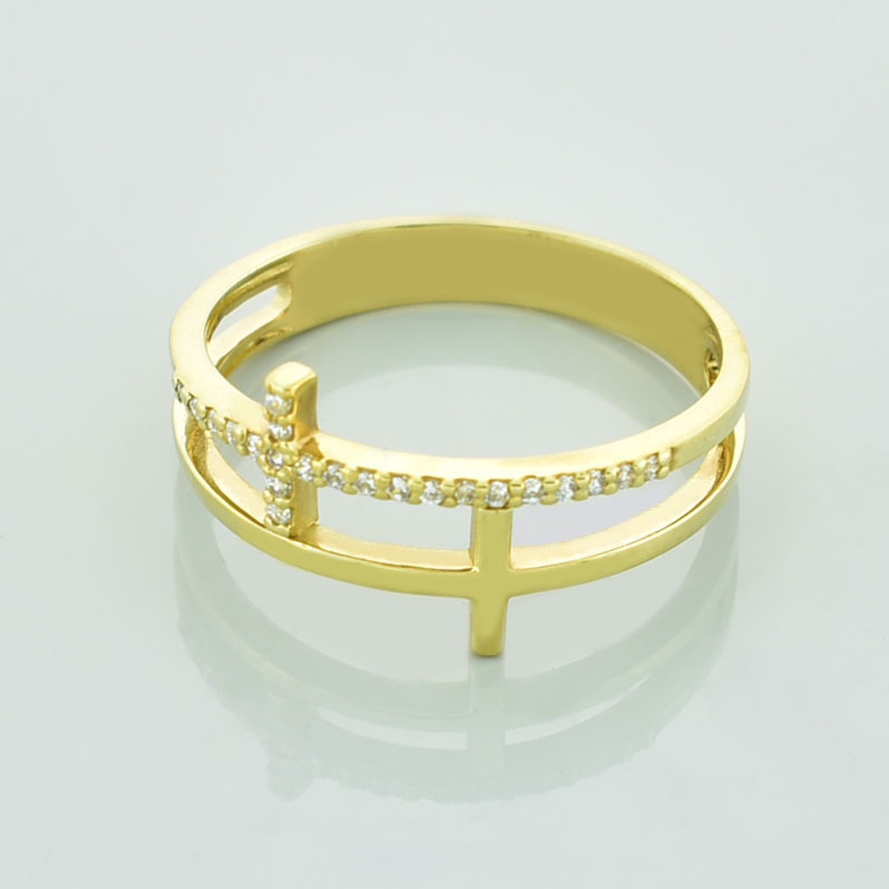 Złoty pierścionek z krzyżami wysadzany diamentami lub cyrkoniami leżący przodem.