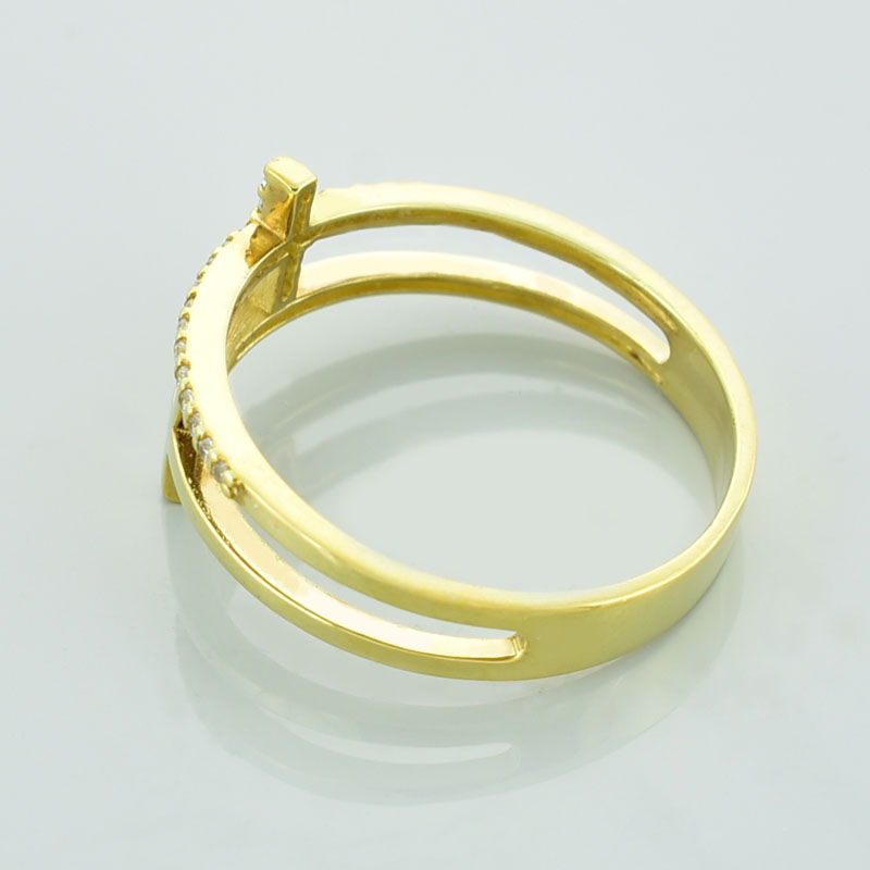 Złoty pierścionek z krzyżami wysadzany diamentami lub cyrkoniami leżący na lewym boku.