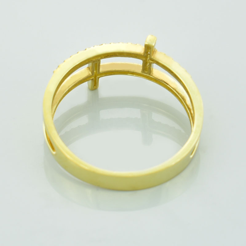 Złoty pierścionek z krzyżami wysadzany diamentami lub cyrkoniami leżący tyłem.