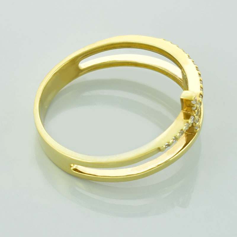 Złoty pierścionek z krzyżami wysadzany diamentami lub cyrkoniami leżący na prawym boku.