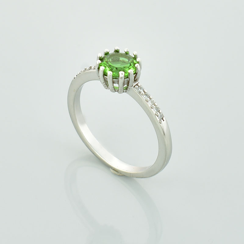 Srerbny pierścionek z okrągłym, zielonym sułtanitem i małymi białymi cyrkoniami na obrączce.