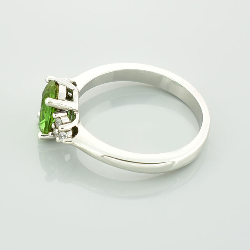 Srebrny pierścionek z zielonym sułtanitem i cyrkoniami po bokach które układają się w kształt trójkata.