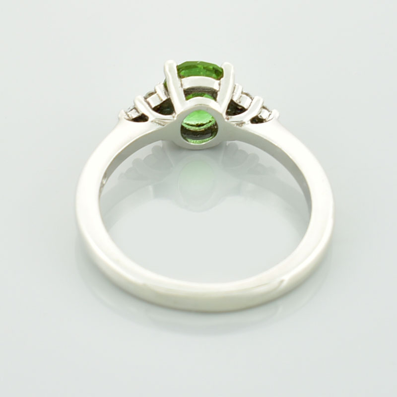 Srebrny pierścionek z zielonym sułtanitem i cyrkoniami po bokach które układają się w kształt trójkata.