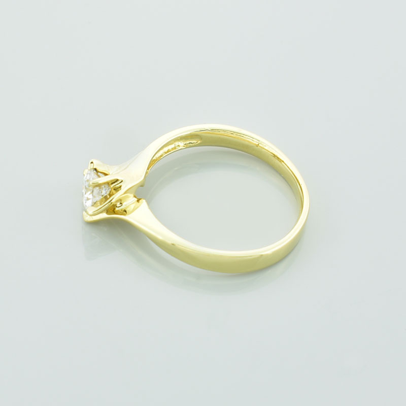Złoty pierścionek z moissanitem leżący na lewym boku.