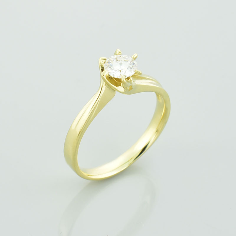 Złoty pierścionek z moissanitem postawiony bokiem.