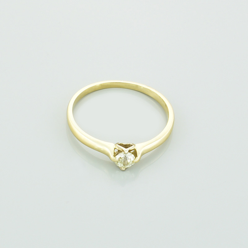 Złoty pierścionek z brylantem serce leżący przodem.
