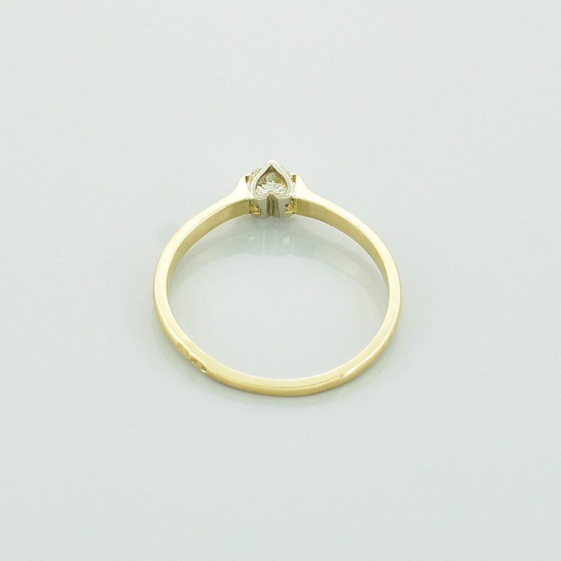 Złoty pierścionek z brylantem serce leżący tyłem.