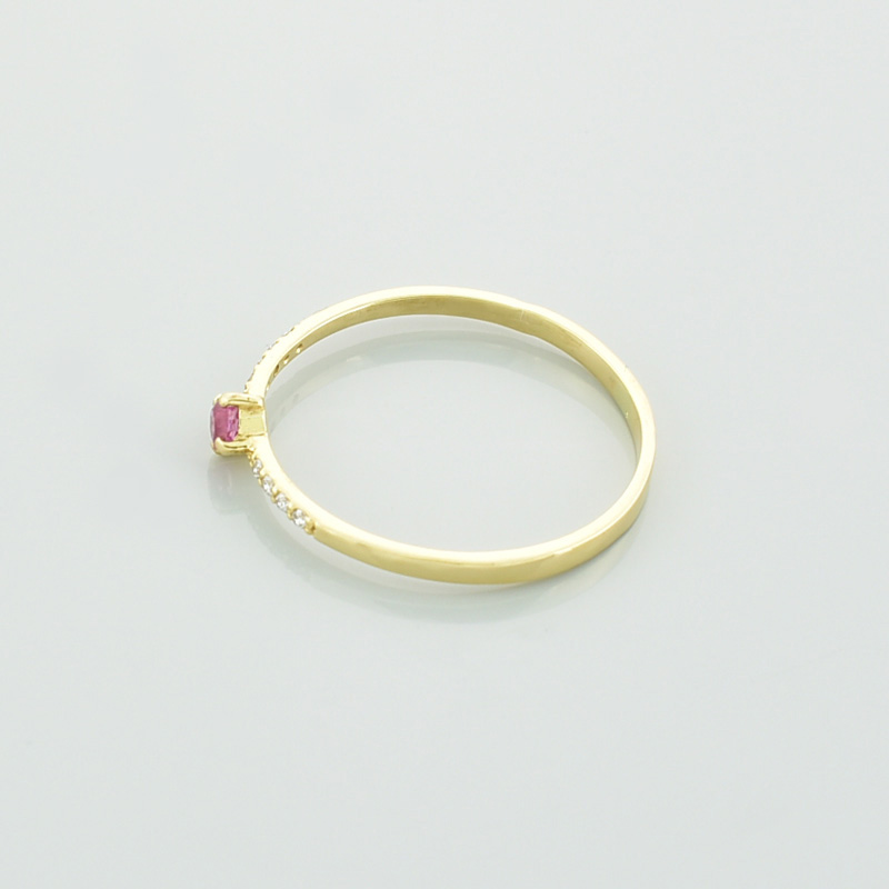 Złoty pierścionek z turmalinem i brylantami. Różowy turmalin i brylanty. Leżący na lewym boku.