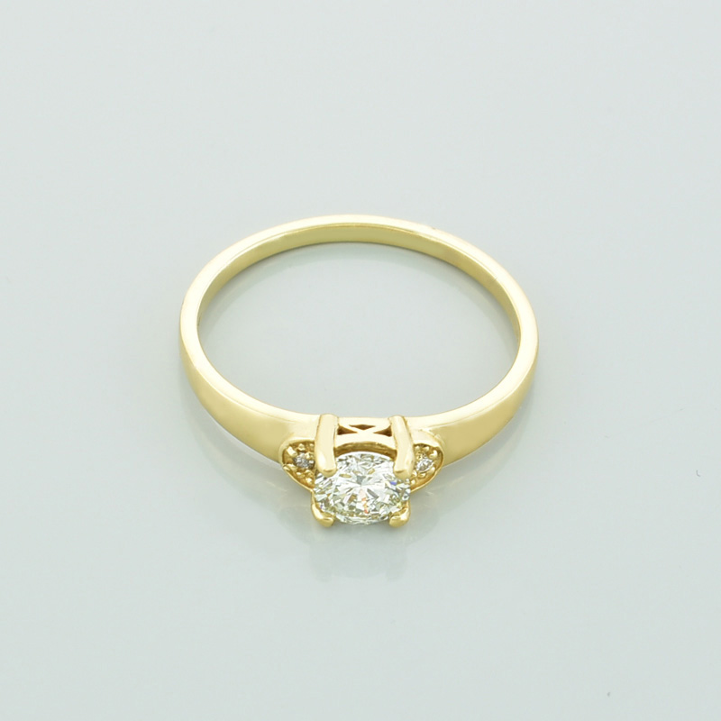 Złoty pierścionek z diamentami leżący przodem.
