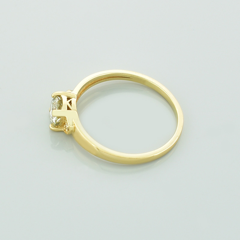 Złoty pierścionek z diamentami leżący na lewym boku.