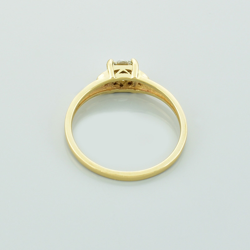 Złoty pierścionek z diamentami leżący tyłem.