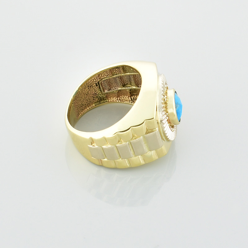 Złoty sygnet z naturalnym turkusem i obrączką imitującą bransoletę zegarkową leżący na prawym boku.