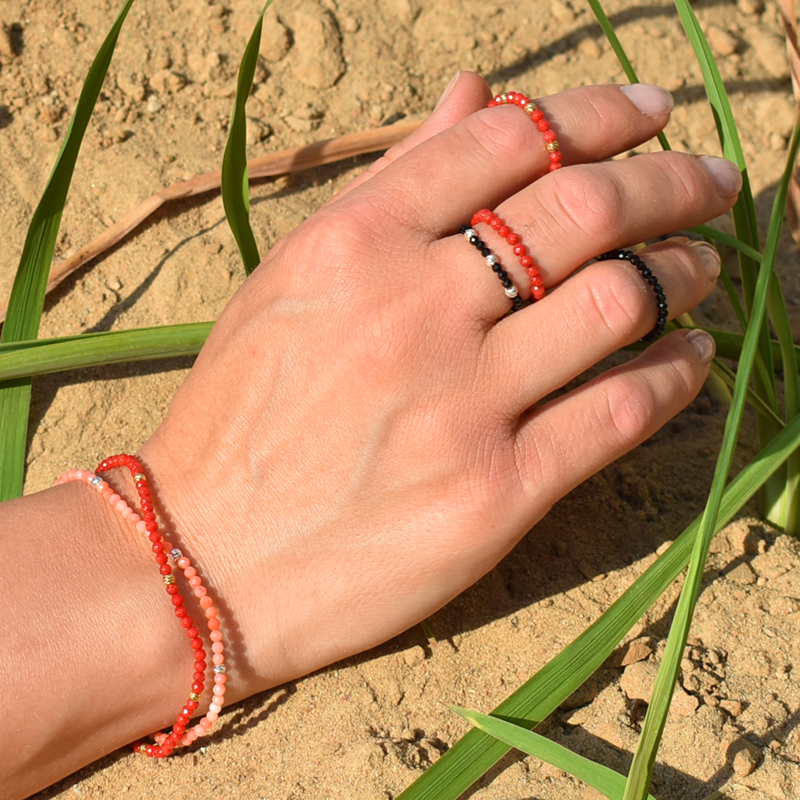 Elastyczne pierścionki i bransoletki z koralami i spinelami na dłoni.