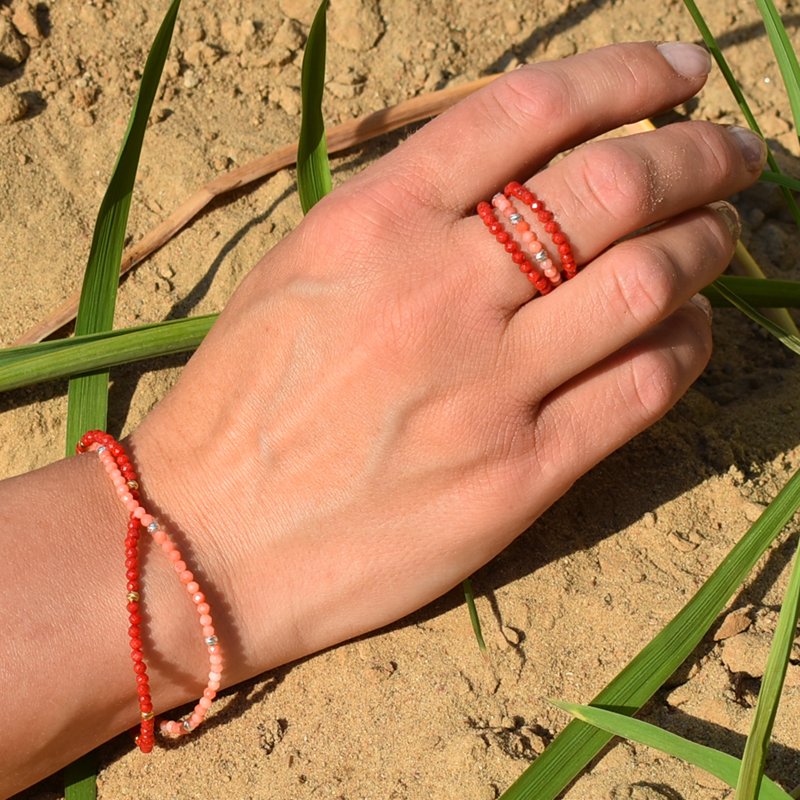 Elastyczne pierścionkii bransoletki z koralami przedstawione na dłoni.