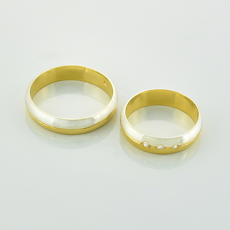 Obrączki z brylantami półokrągłe dwukolorowe z białego i żółtego złota, leżące obok siebie.