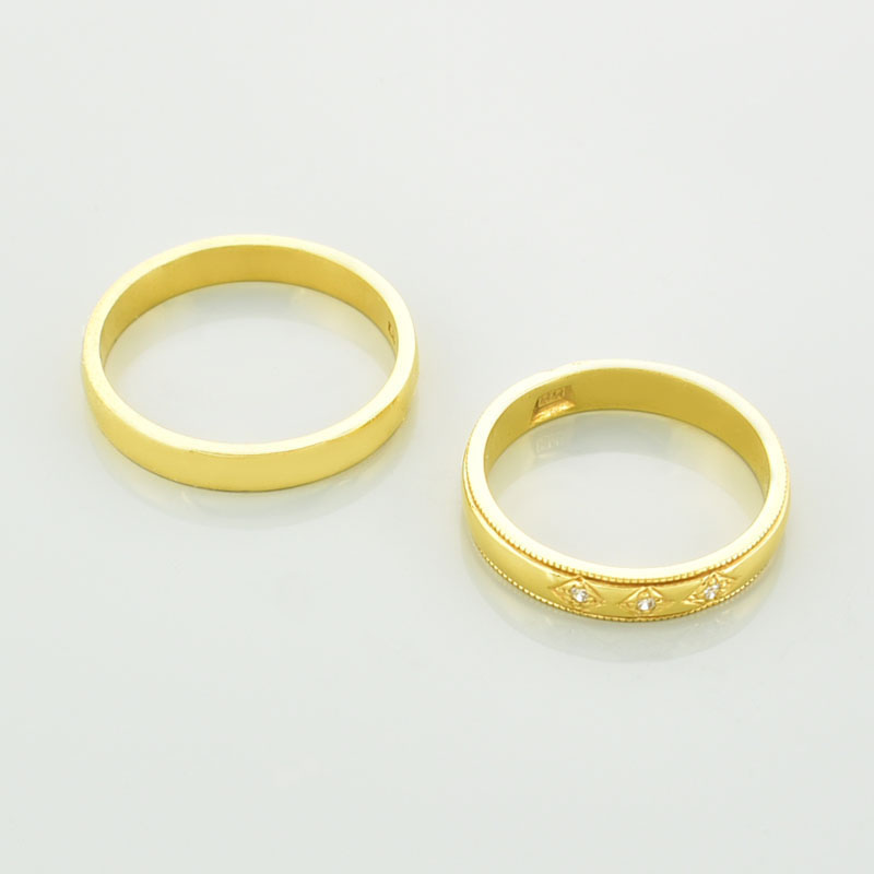 Obrączki ślubne z brylantami w żółtym złocie 585 próby leżące jedna obok drugiej.