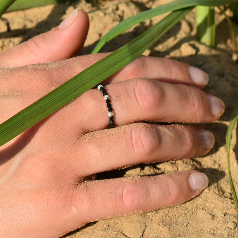 Elastyczny pierścionek ze spinelami i srebrem zaprezentowany na dłoni.