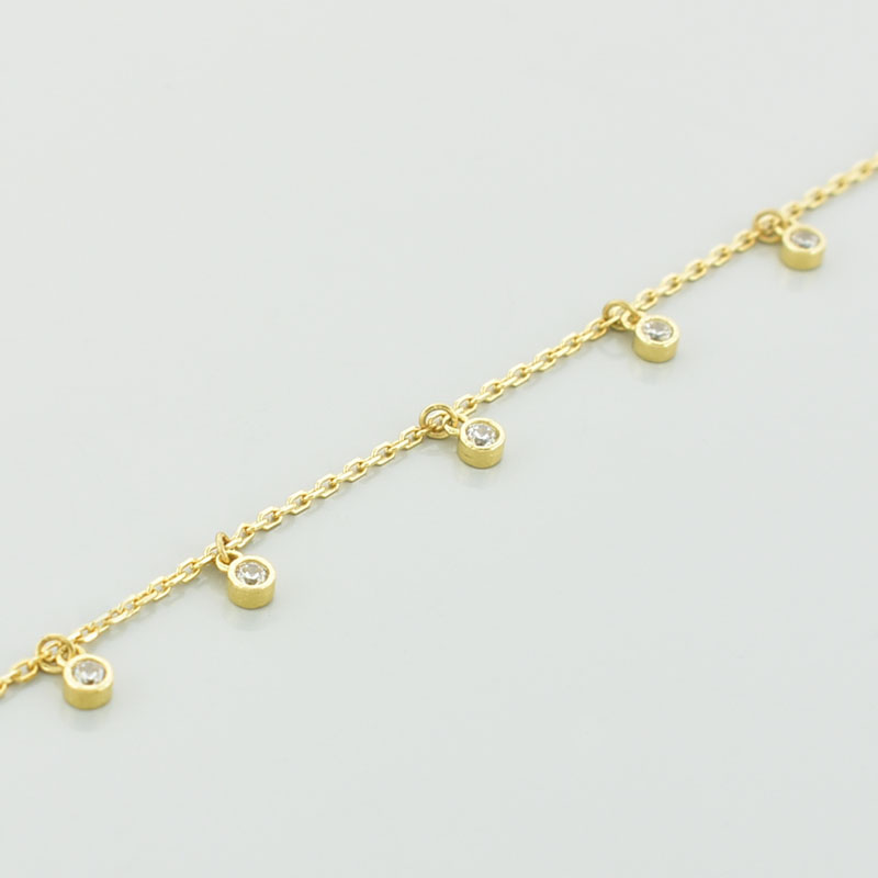 Złota bransoletka łańcuszkowa z białymi cyrkoniami w zbliżeniu.