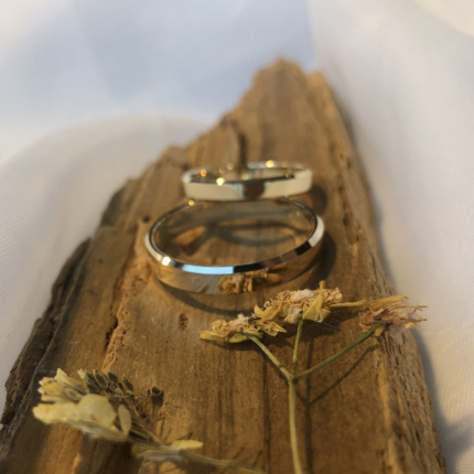 Klasyczne obrączki ślubne wykonane ze złota leżące na kawałku drewna.