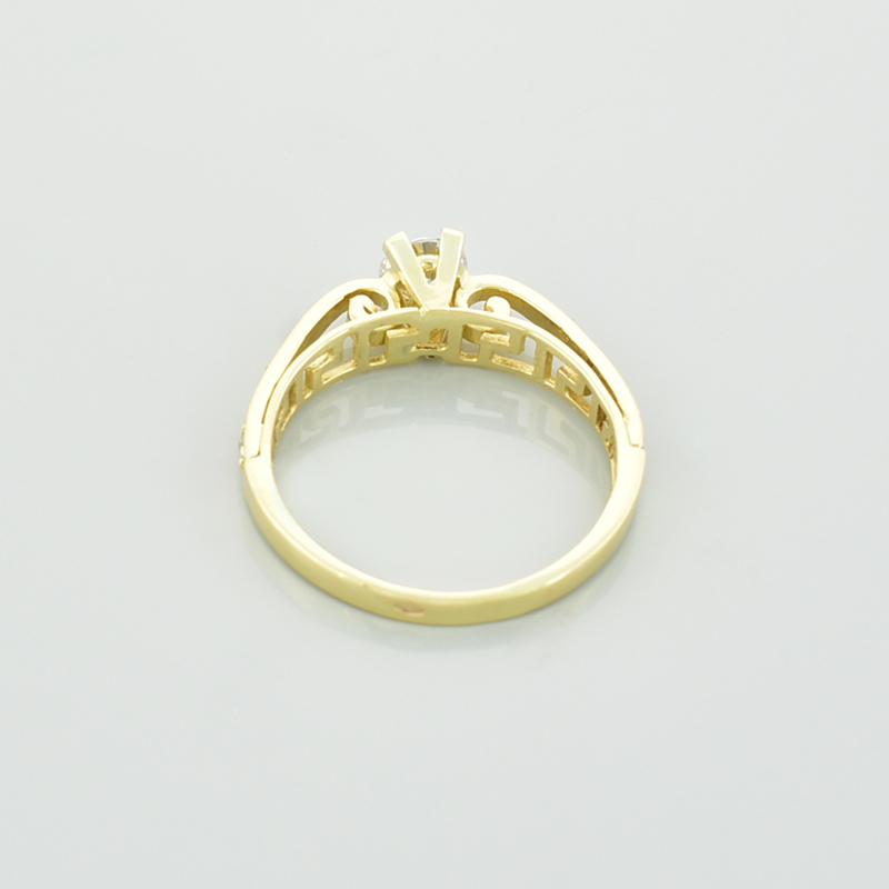 Złoty pierścionek z cyrkoniami leżący tyłem.