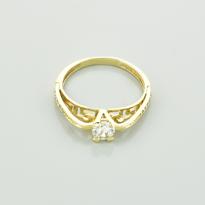 Złoty pierścionek z cyrkoniami leżący przodem.