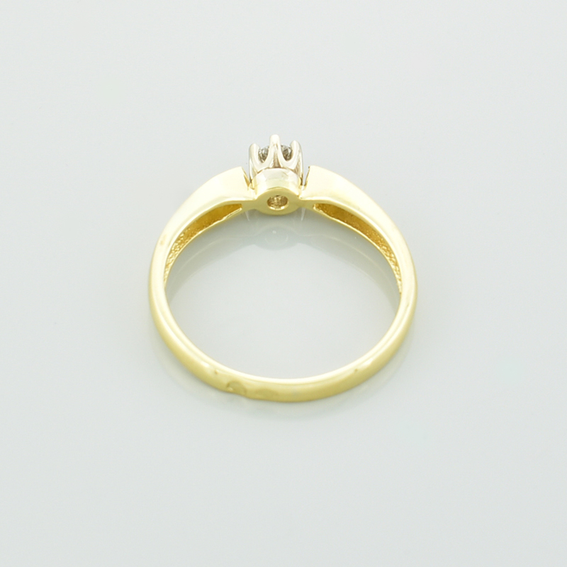 Złoty klasyczny pierścionek z brylantem leżący tyłem.