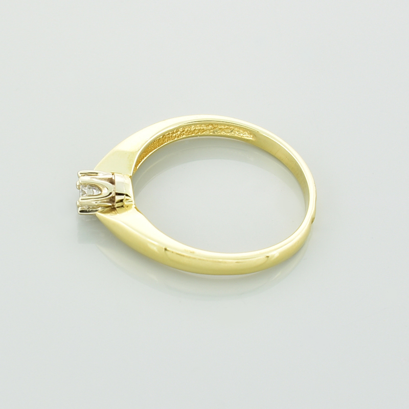 Złoty klasyczny pierścionek z brylantem leżący bokiem.
