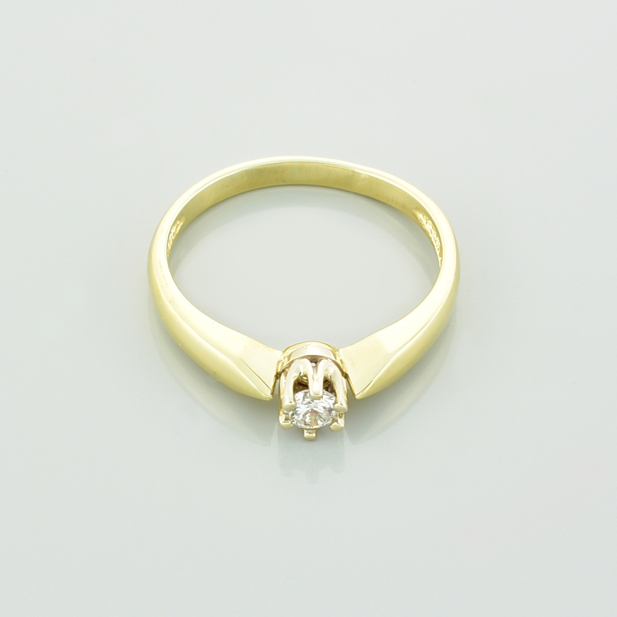 Złoty pierścionek zaręczynowy z brylantem leżący przodem.