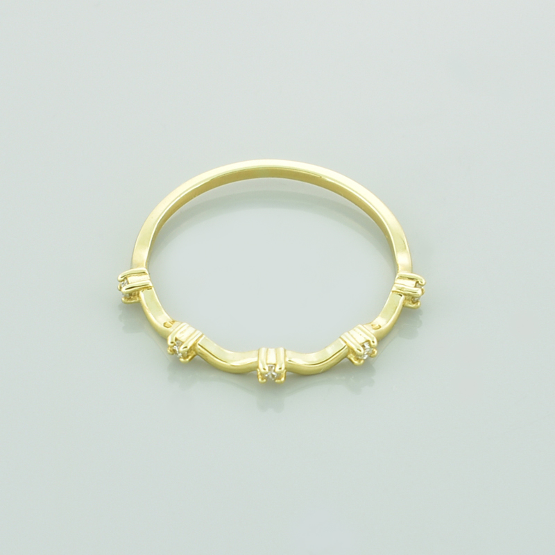 Złoty pierścionek z brylantami fala leżący przodem.