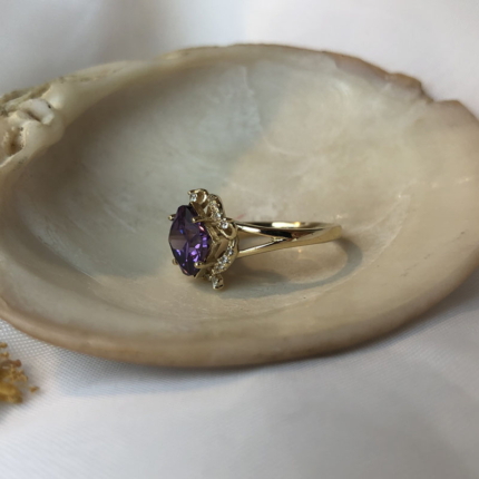 Złoty pierścionek z fioletowym kamieniem pokazany bokiem.