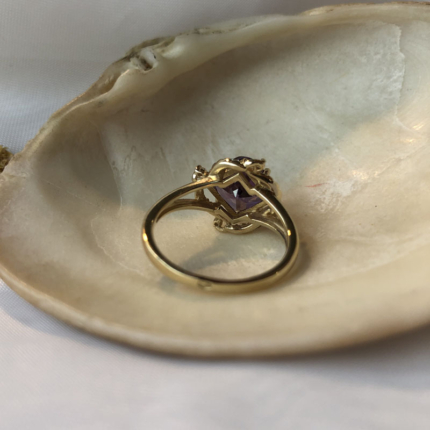 Złoty pierścionek z fioletowym kamieniem widoczny od tyłu.