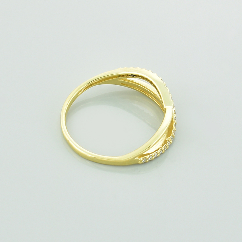Złoty pierścionek z moissanitami i symbolem nieskończoności leżący bokiem.