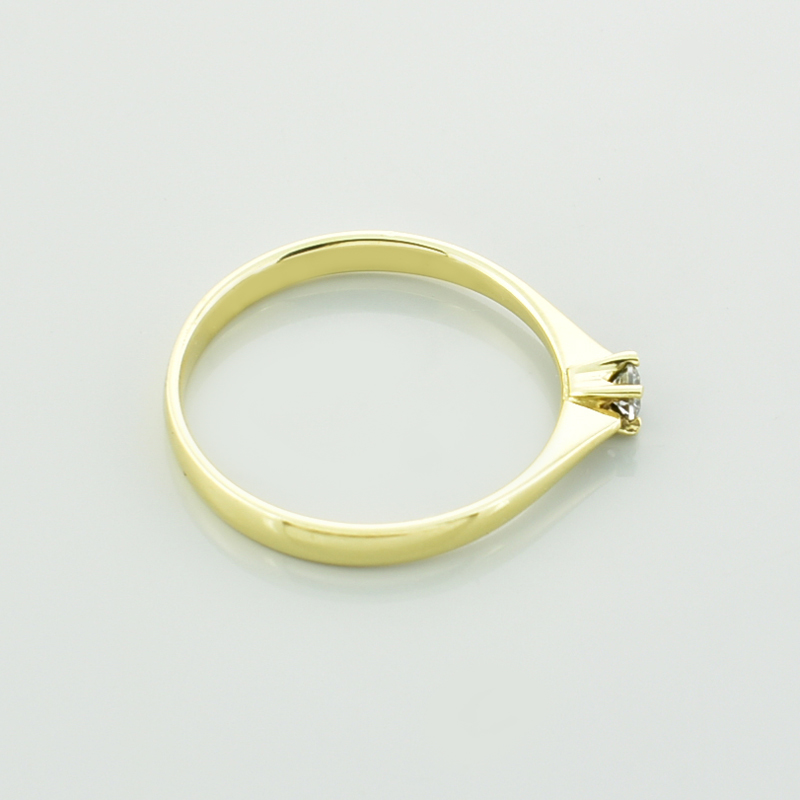 Złoty pierścionek z moissanitem leżący bokiem.