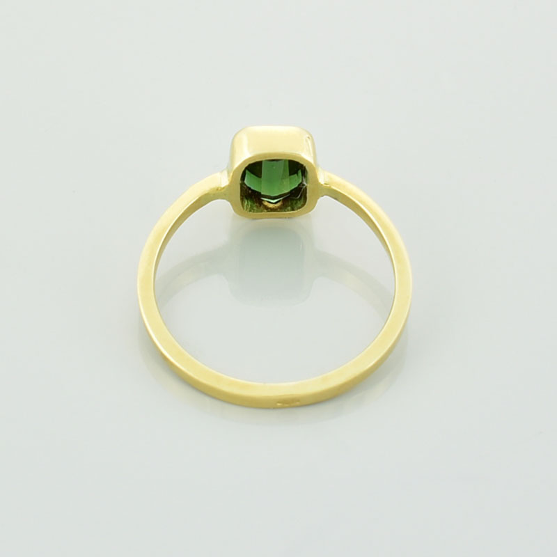 Złoty pierścionek z turmalinem w kolorze zielonym leżący tyłem.
