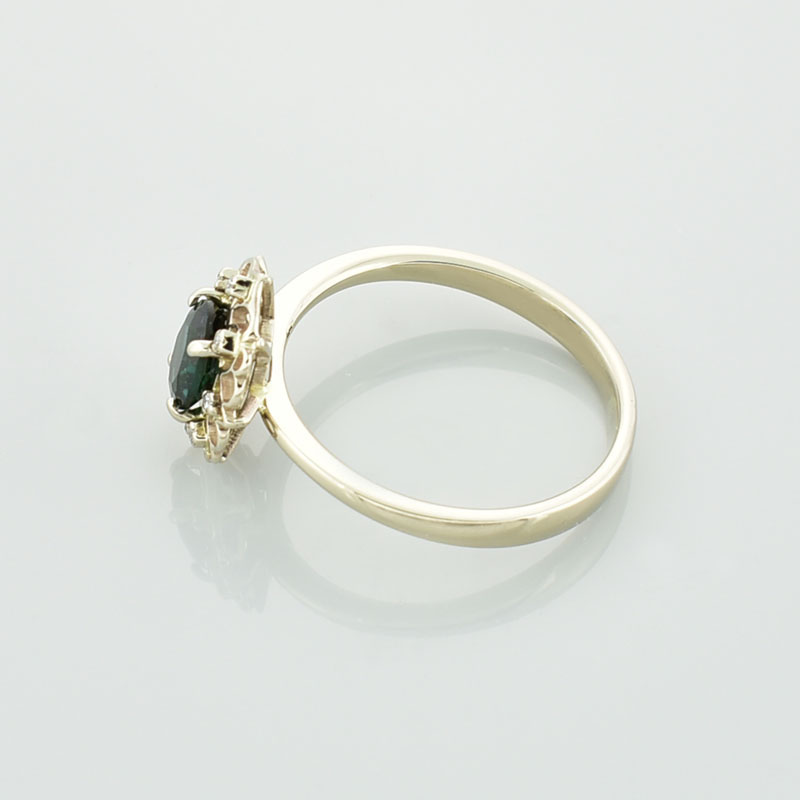 Złoty pierścionek z zielonym tanzanitem i brylantami pokazany od boku.
